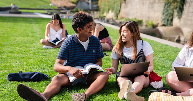 Students studying on the grass beside the Leith.